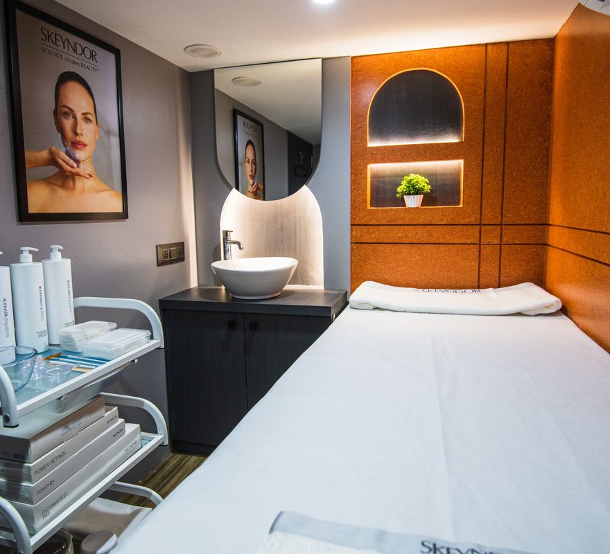 A private treatment room at Ftry Salon, with a made-up treatment bed and a trolley of skincare.